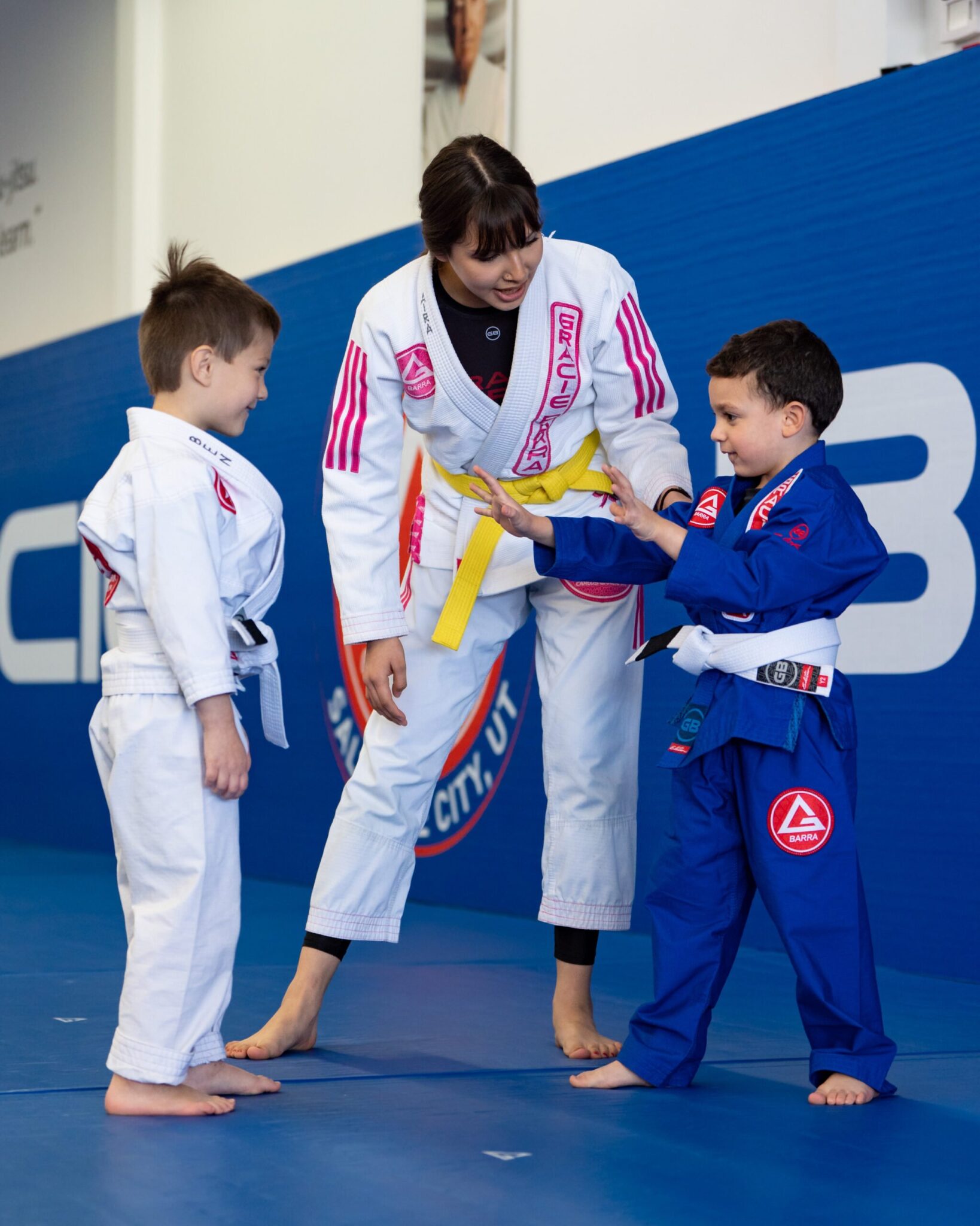 A yellow belt teen student helping two little white belt boys